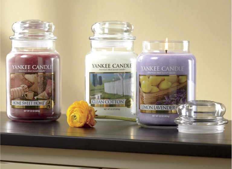 Three scents of Yankee jar candles on a wood shelf.