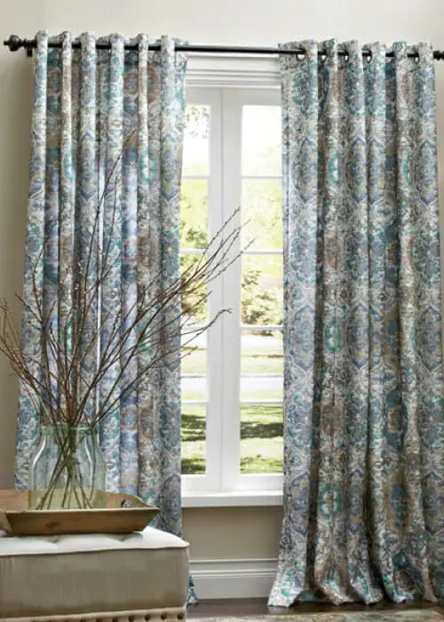 Seven colors of textured grommet panels hung on a single rod, above a sunny window.