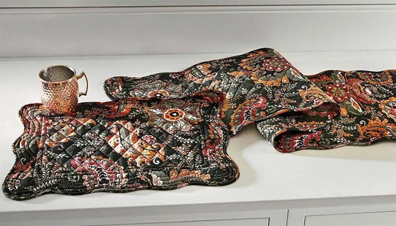 A quilted black paisley print table runner and matching placemat, with a hammered copper moscow mule mug.
