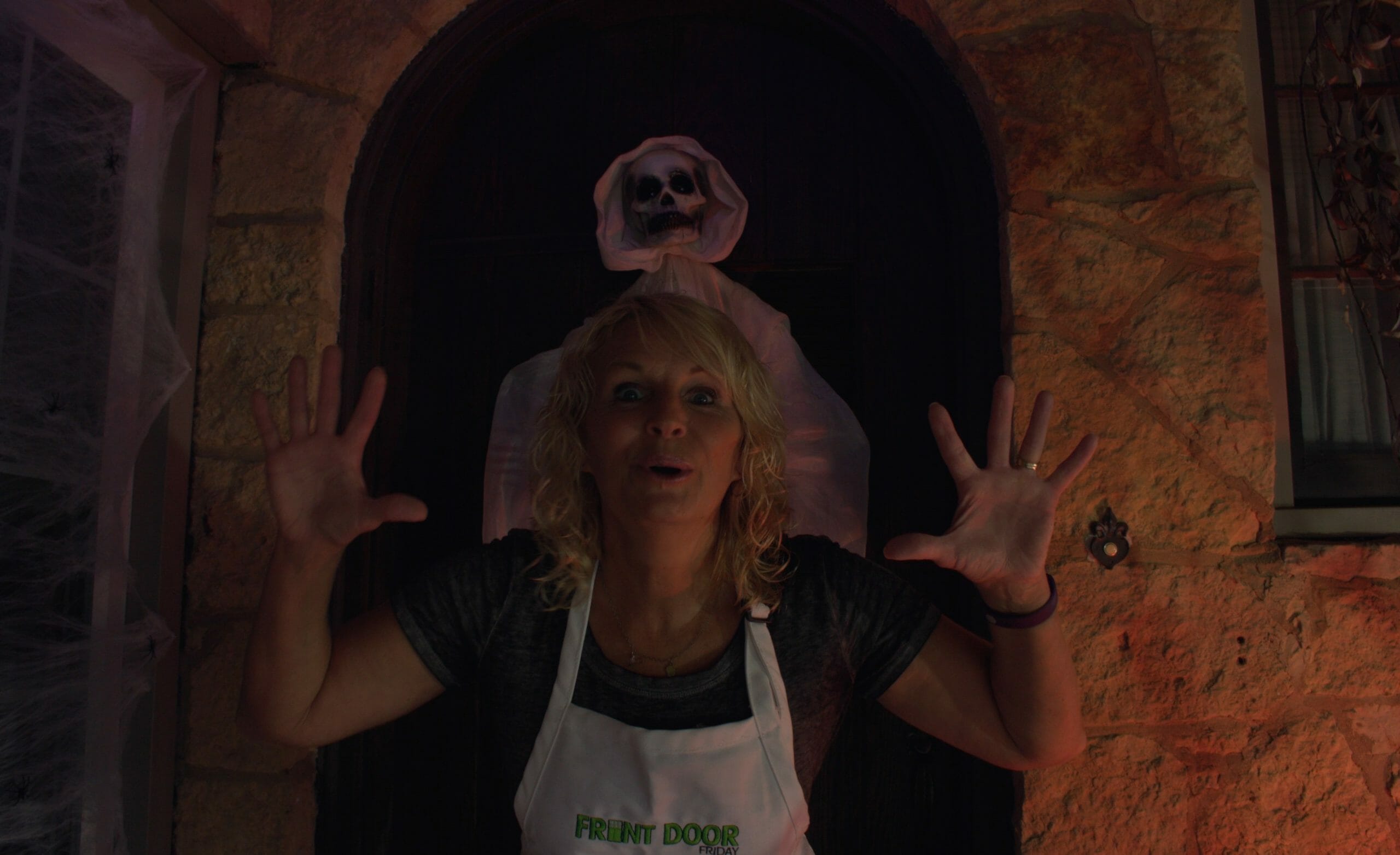 woman on porch in front of a gauze covered ghost that is hanging on door