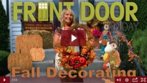 woman holding a round wreath with fall flowers and gourds on it