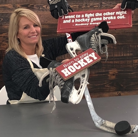 woman with a hockey themed wreath that includes hockey stick puck skates gloves and hockey sign