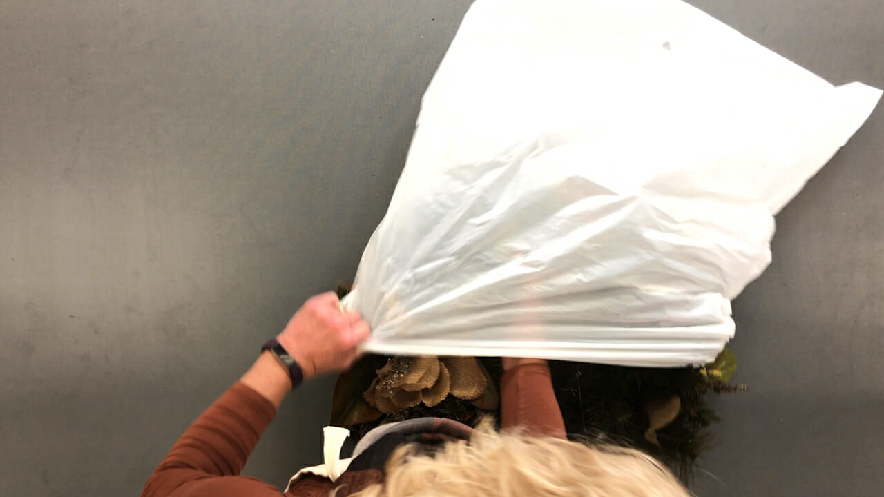 woman placing wreath in plastic bag for storage