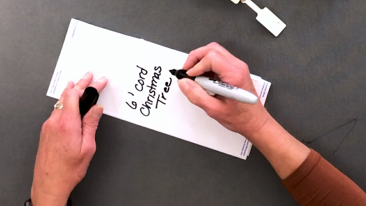 woman using black marker to create label for extension cord storage