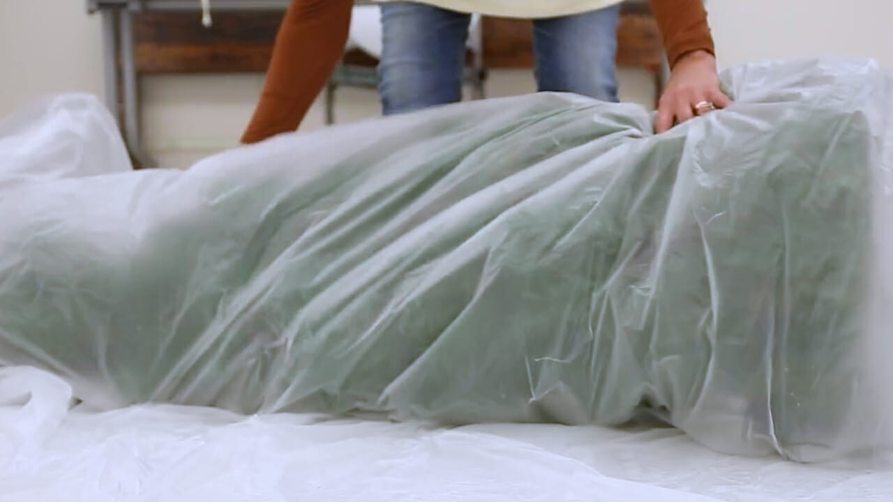 woman wrapping up a Christmas tree in plastic for storage