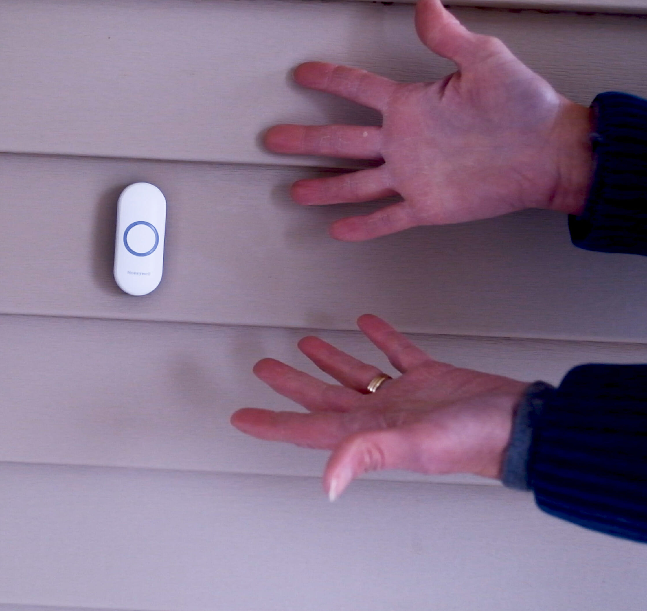 woman showing doorbell on outside wall
