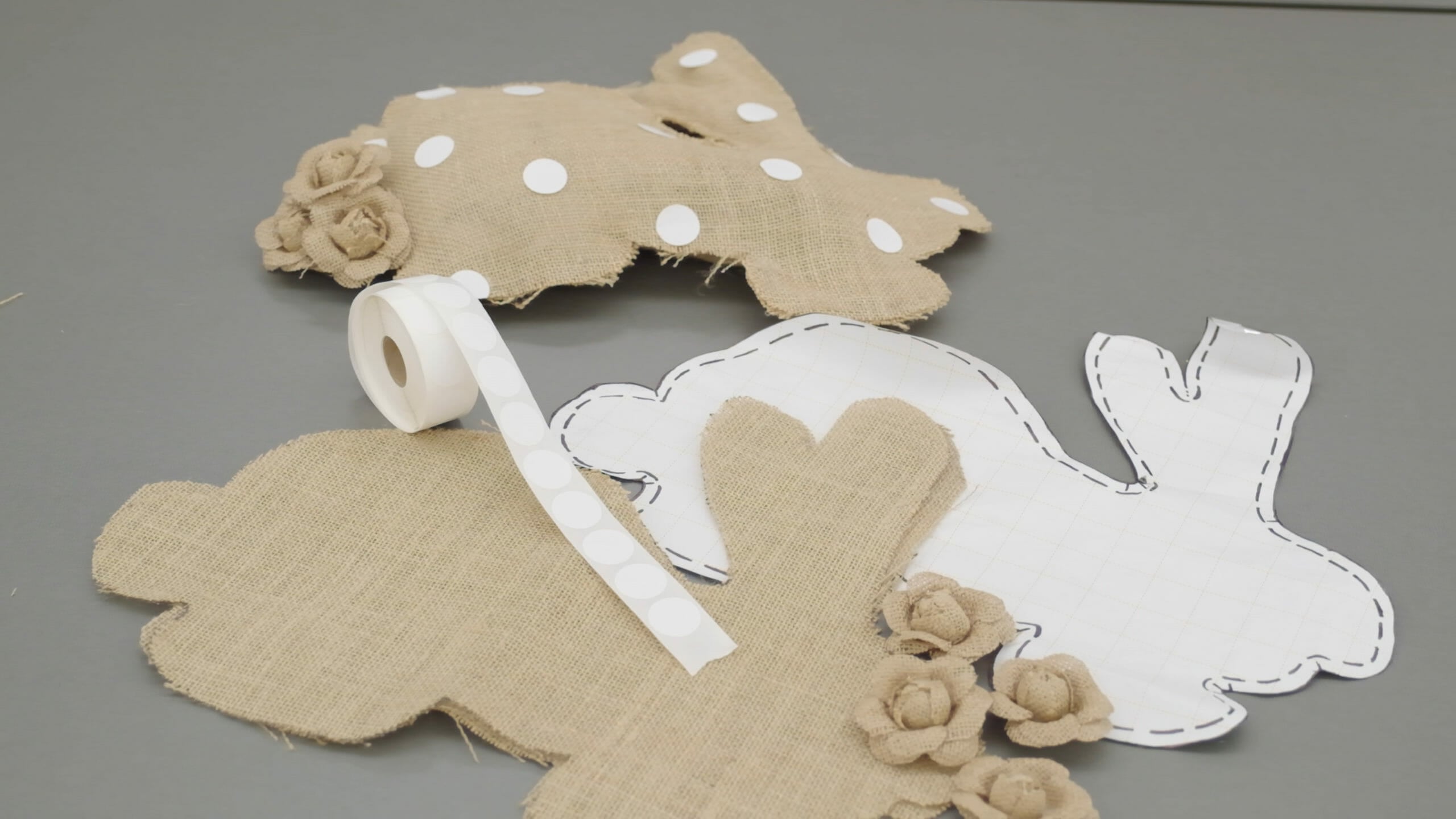 A rabbit pattern with stitching lines, cut burlap pieces and a stitched rabbit with a burlap flowers tail and white dots.