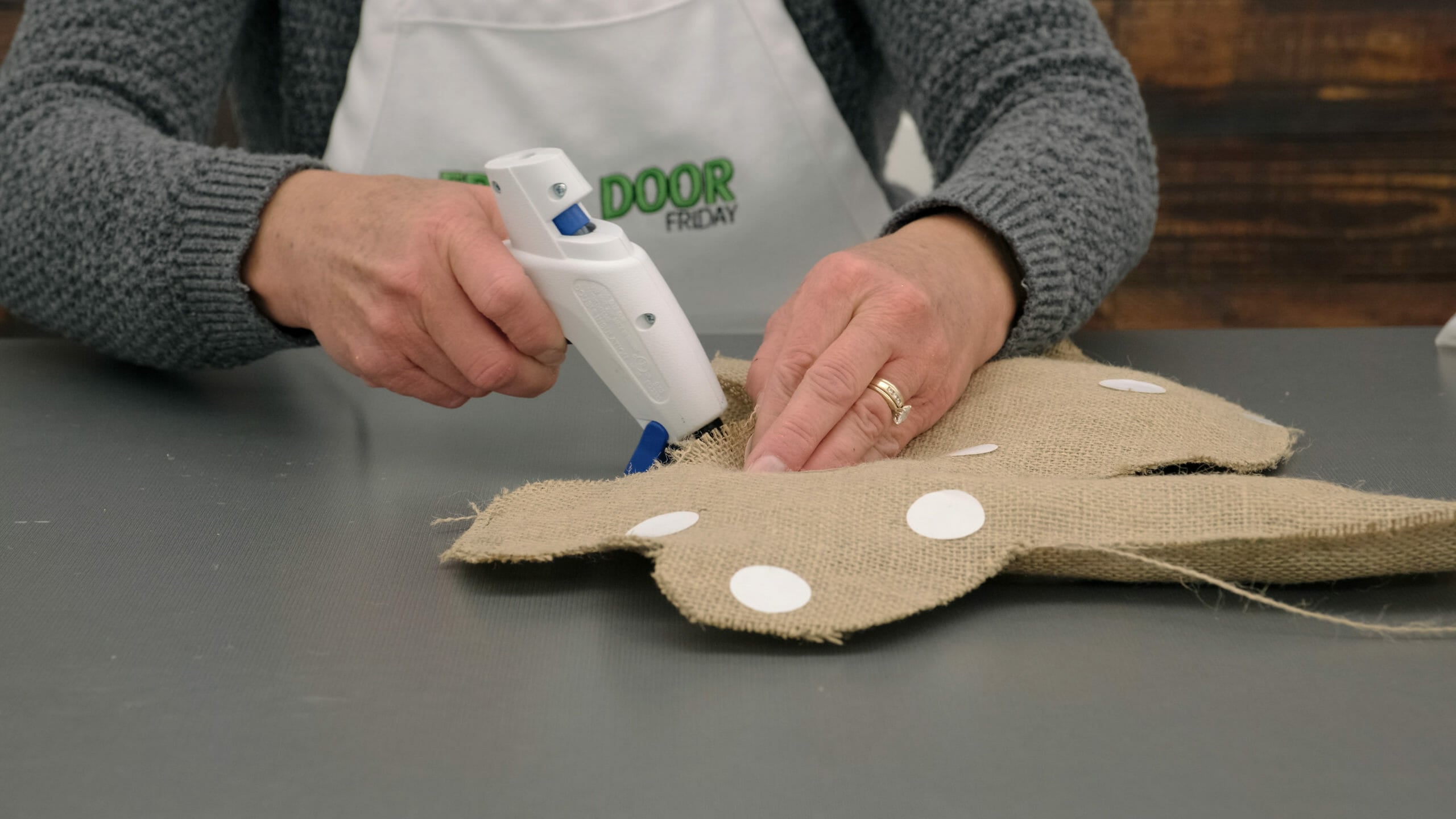 woman using hot glue to make a burlap bunny pillow