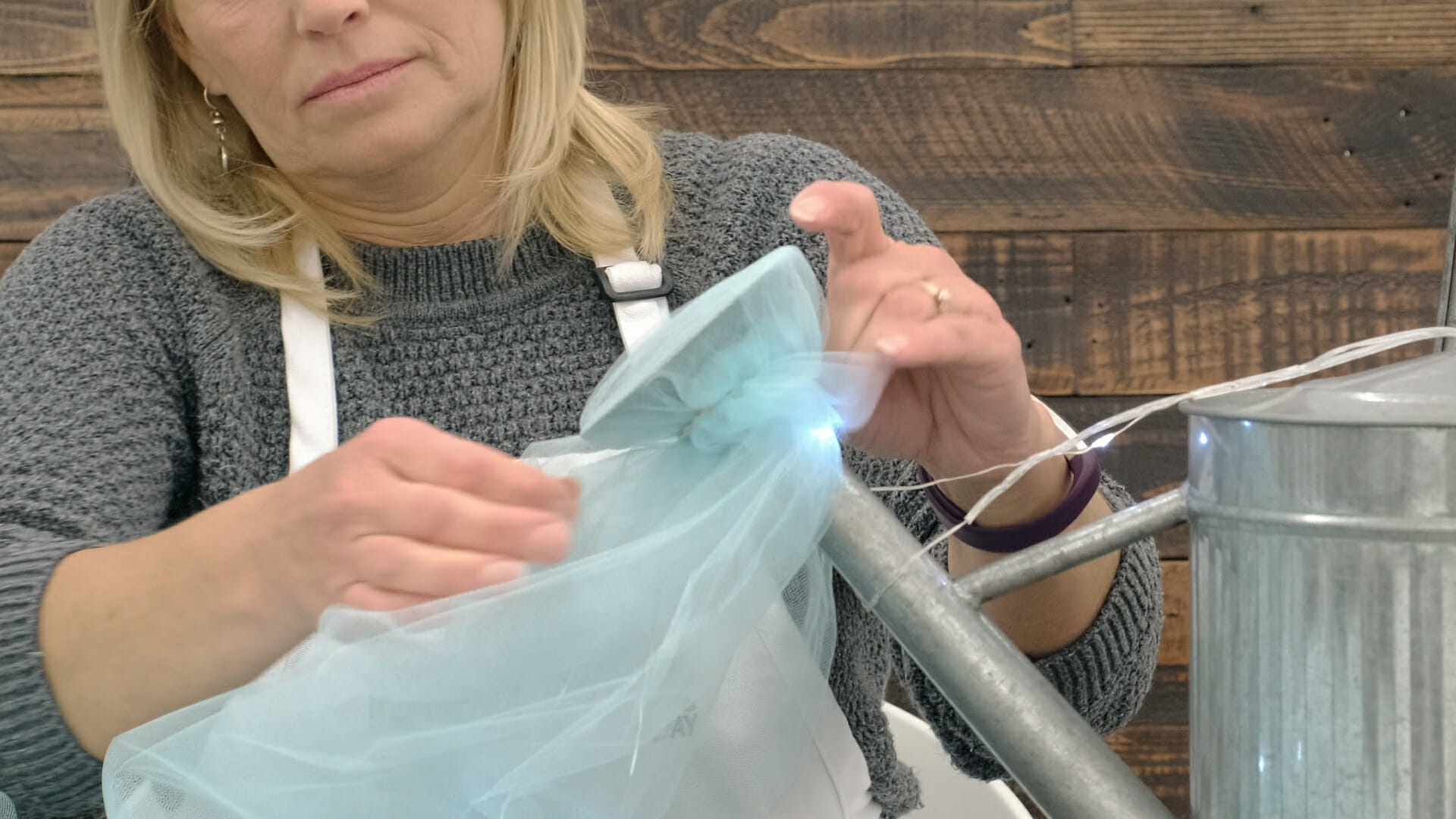 woman tying tulle fabric to a watering can