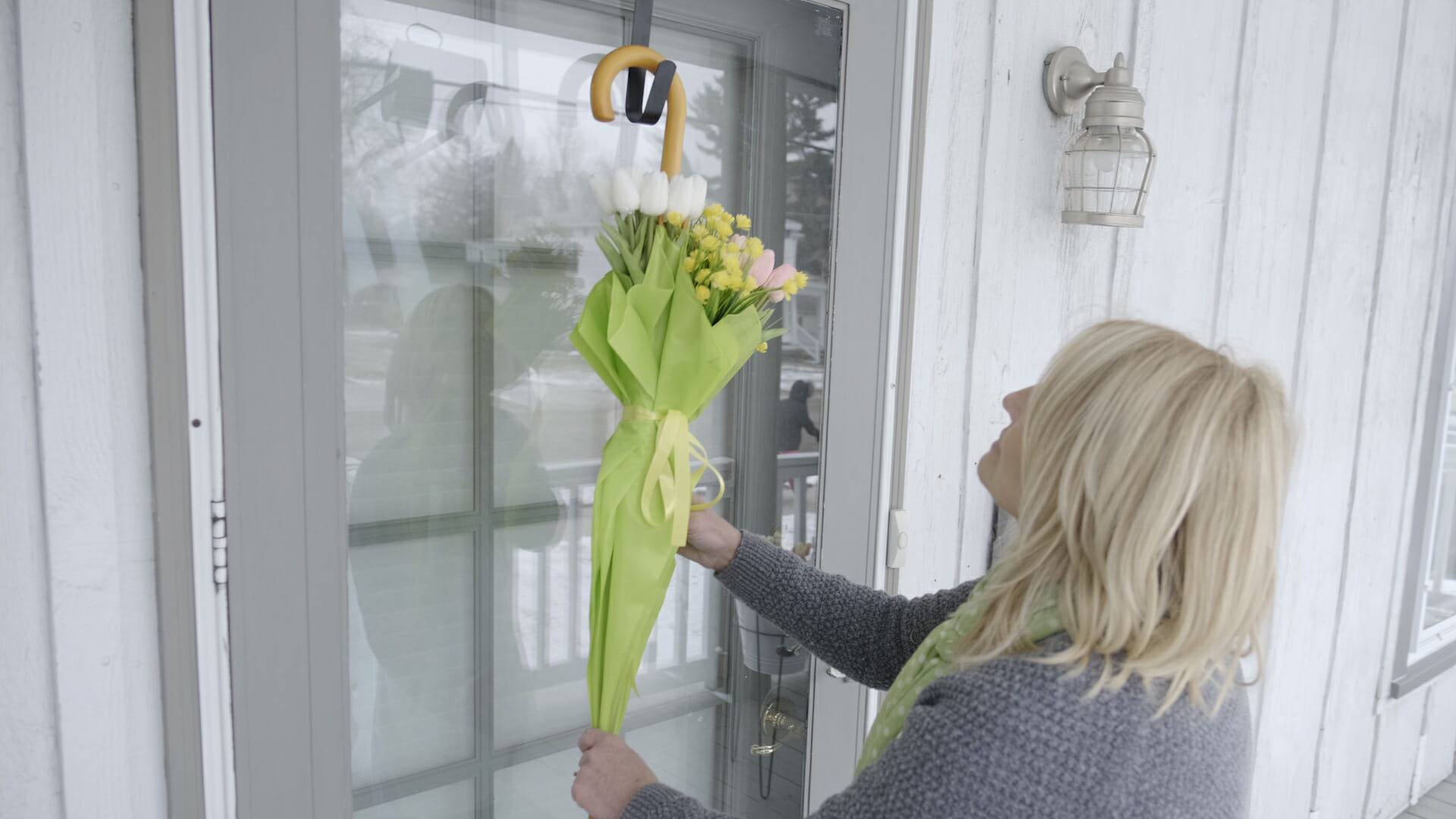 woman hanging an umbrella wreath with spring flowers in it