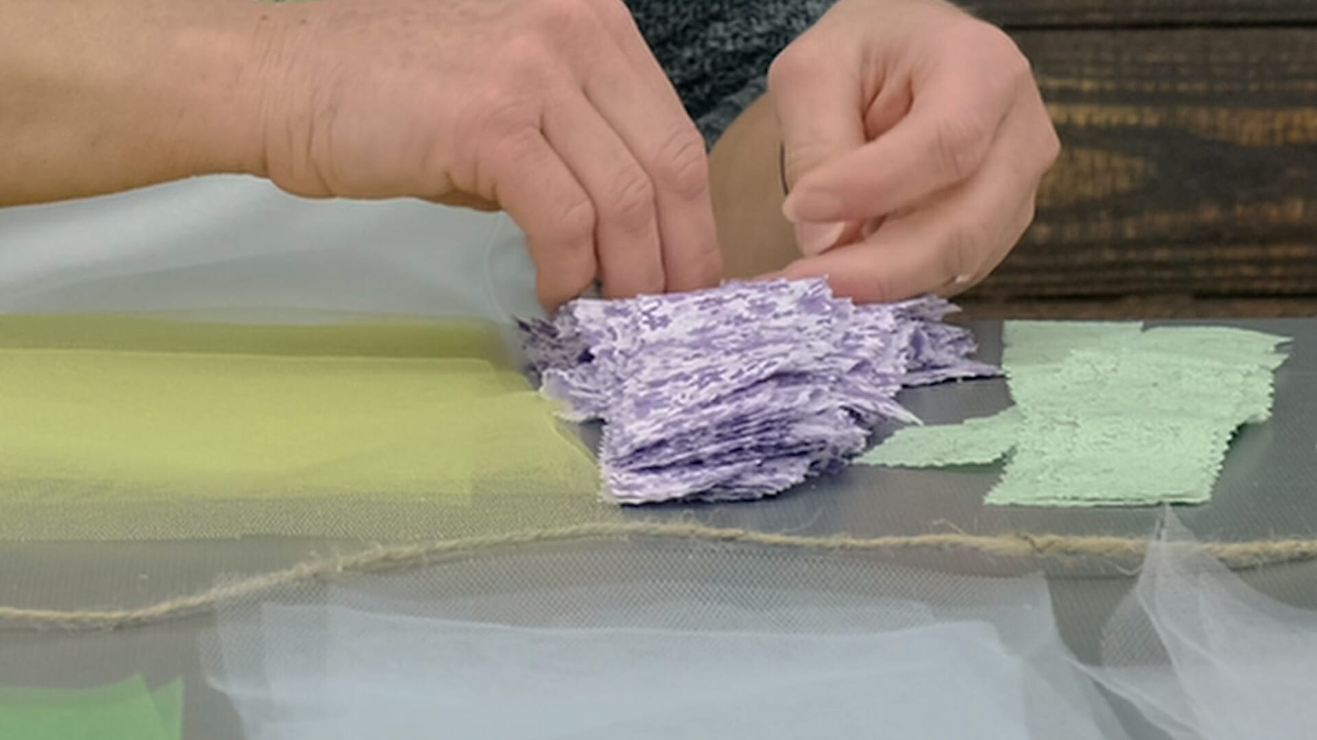Close up view of a woman's hands and stacks of tulle squares and calico cut with pinking shears.