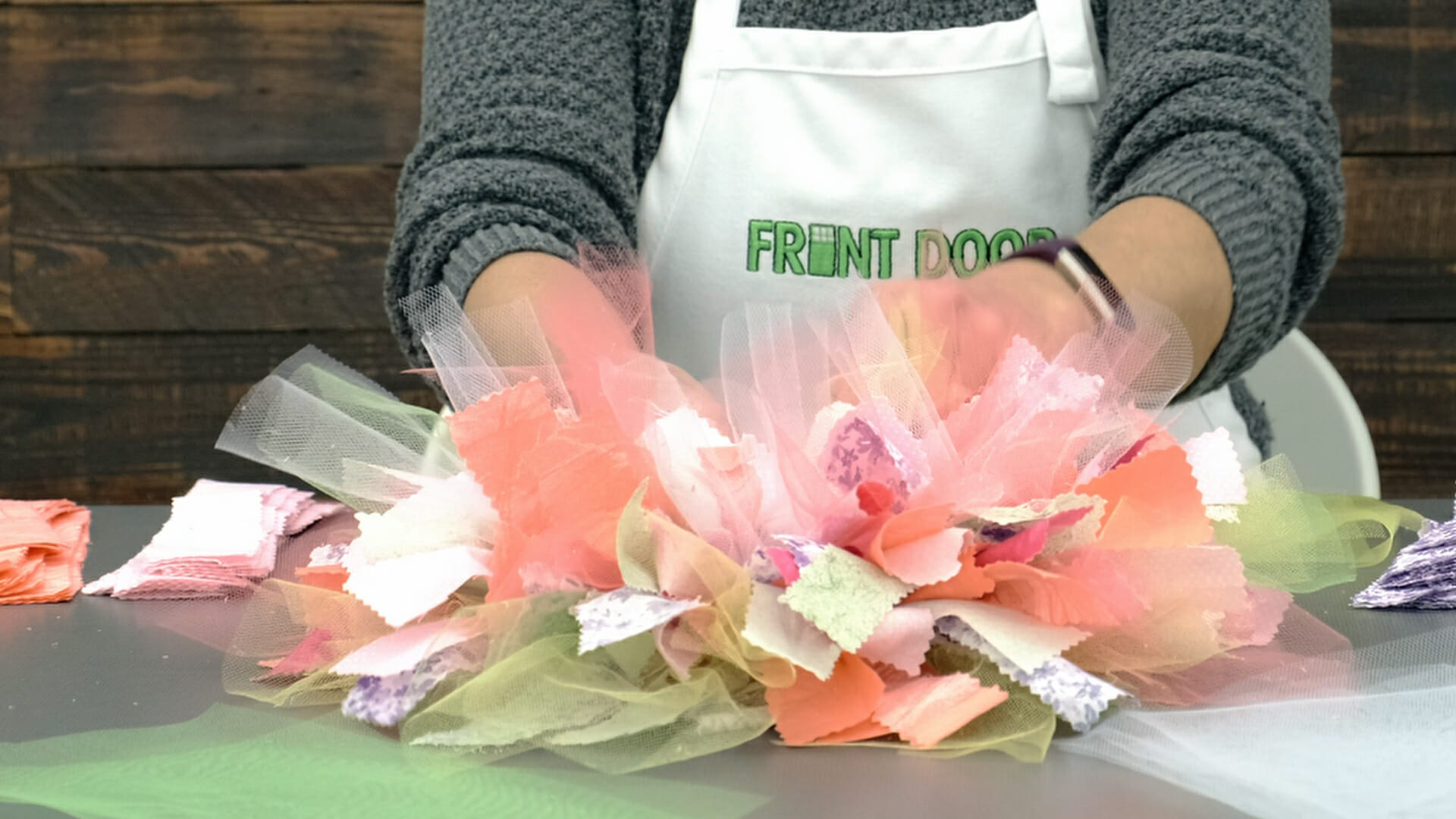 Close up view of a woman's hands assembling a colorful rag wreath.