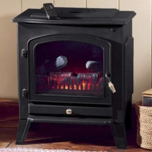 A lit, small black electric fireplace in a rustic wood stove shape, placed on a wood floor.