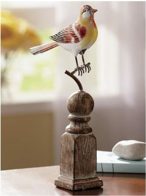 A yellow, red, white, and brown bird figurine on a restice turned wood base.