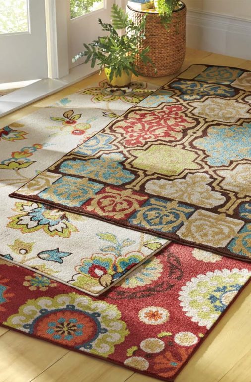 Three stacked contemporary floral area rugs in different designs, but in same colors of red, teal, lime, brown, and ivory.