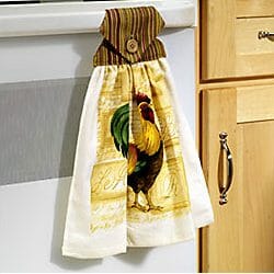 A rooster kitchen towel hanging from a white oven handle by a buttoned flap.