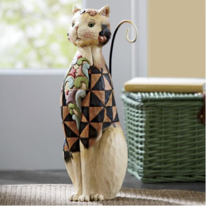 A sitting white Folk Art cat with a black and tan quilt front and a multicolor paisley design.