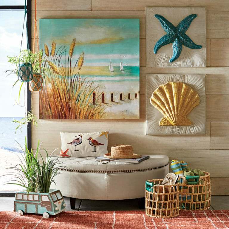 Coastal living area with large beach canvas, starfish and shell plaques, and a shorebirds pillow on a white storage bench.