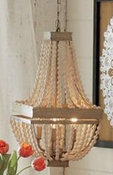 A lit gold pendant chandelier with multiple strands of beads.