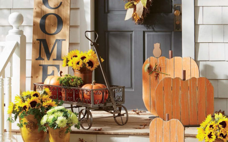metal wagon with pumpkins, sunflowers in potted plant and three wooden distressed pumpkin signs