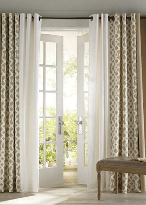 Three pairs of grommet window curtains on a single rod over French doors, in beige, white, and a beige trellis pattern.