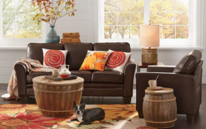 colors of fall adorn this Livingroom with throw pillows, vase with sprigs of fall leaves and a quilt over the couch