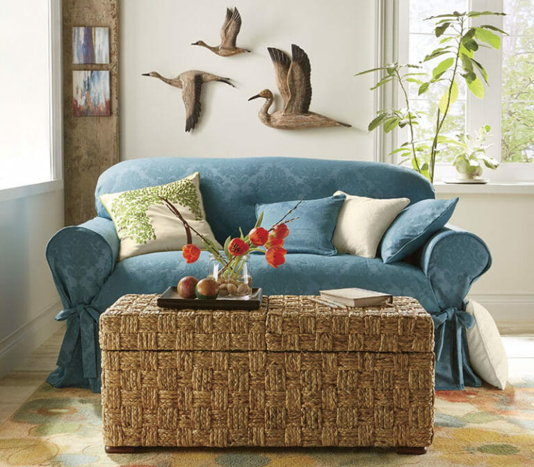 Living room decor with loveseat with blue slipcover and basket-style storage coffee table