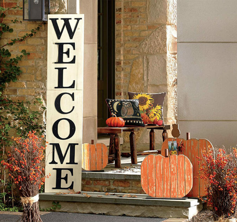 large black and white vertical welcome sign with bench with owl and sunflower pillows and 3 wooden pumpkin decor