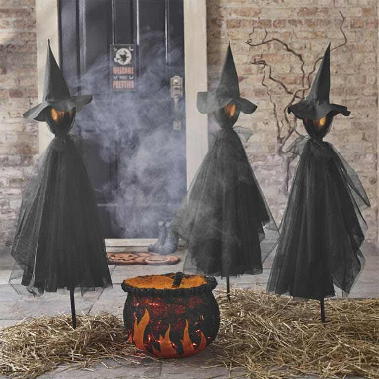 Black witch stake decorations outside with orange and black cauldron and smoke
