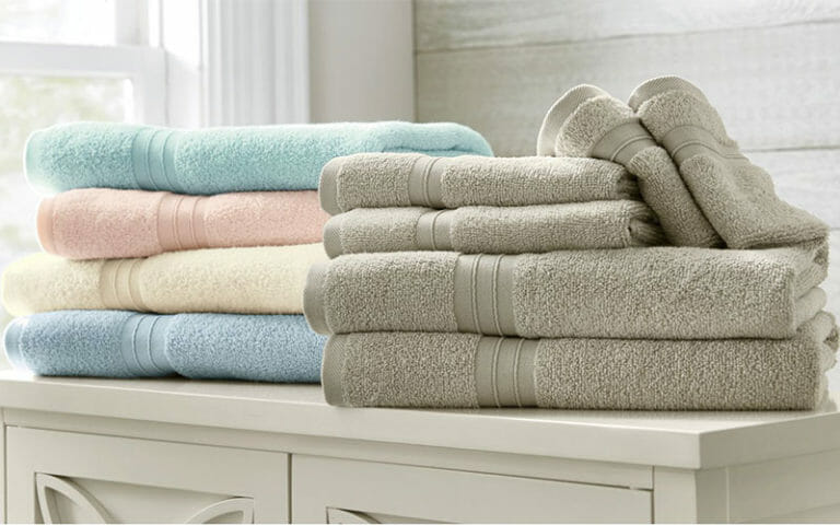 A stack of five folded pastel bath towels, in seafoam, peach, yellow, blue, and ecru.