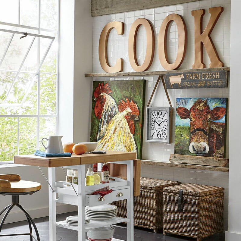 Kitchen wall art, including large wood COOK letters, a cow and two roosters canvases, and two woven storage baskets.