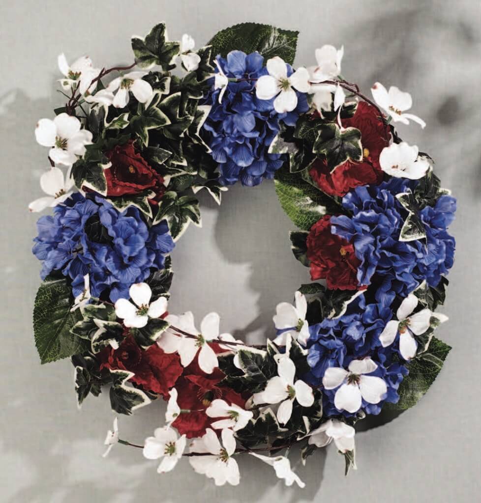Patriotic round wreath with red poppies, white apple blossoms, and blue hydrangeas.