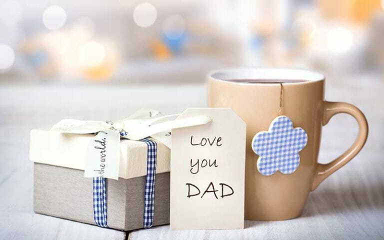 A ribbon tied box next to a tan mug of coffee, and Love you DAD written on a card.