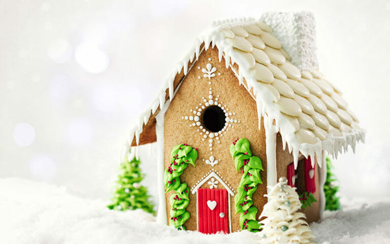 A Gingerbread-House with white iced cookie roof, a red door and shutters, and green icing ivy.