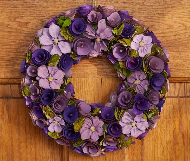 purple flowers made of wood on a lightweight wreath with a rope hanger
