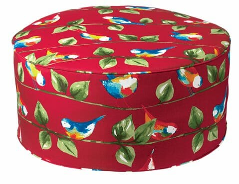 A multicolor ottoman with a birds on twigs pattern.