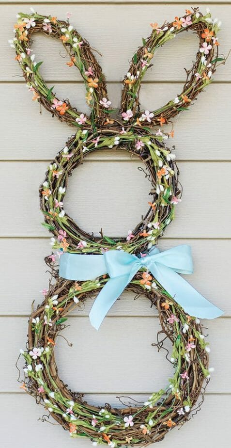 Four grapevine wreaths wrapped with pastel flower sprigs and tied with a blue ribbon to create an Easter bunny wreath.