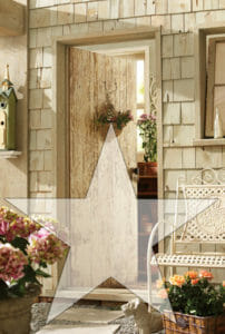 Rustic front door with a basket and planters of flowers, and a white woven metal bench, with a screened star overlay.