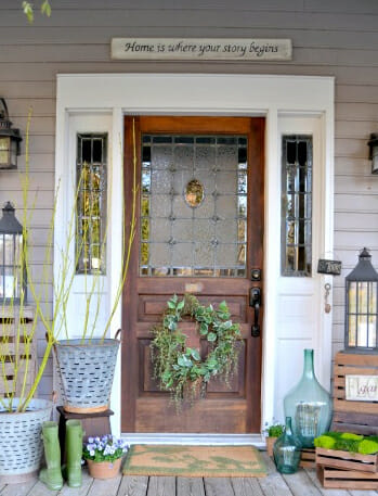 a wreath, galvanized buckets and old crates with greenery create a Spring flea market chic porch