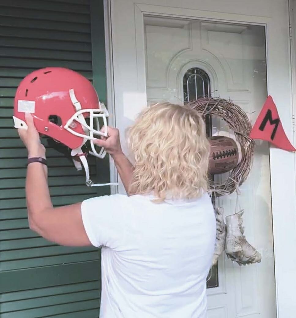 woman hanging football helmet on front porch for football inspired fall theme