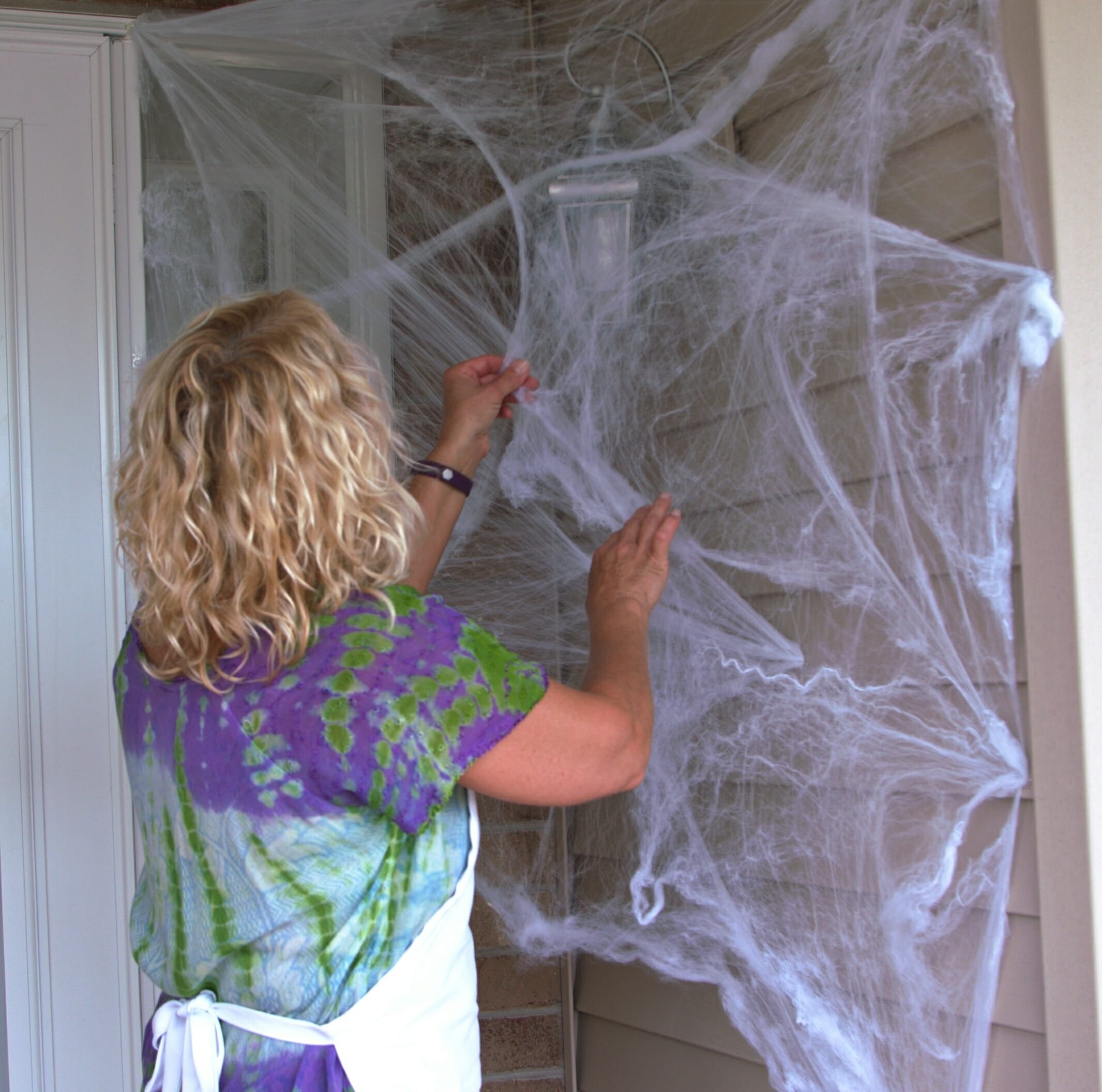 woman hanging cobwebs on front porch