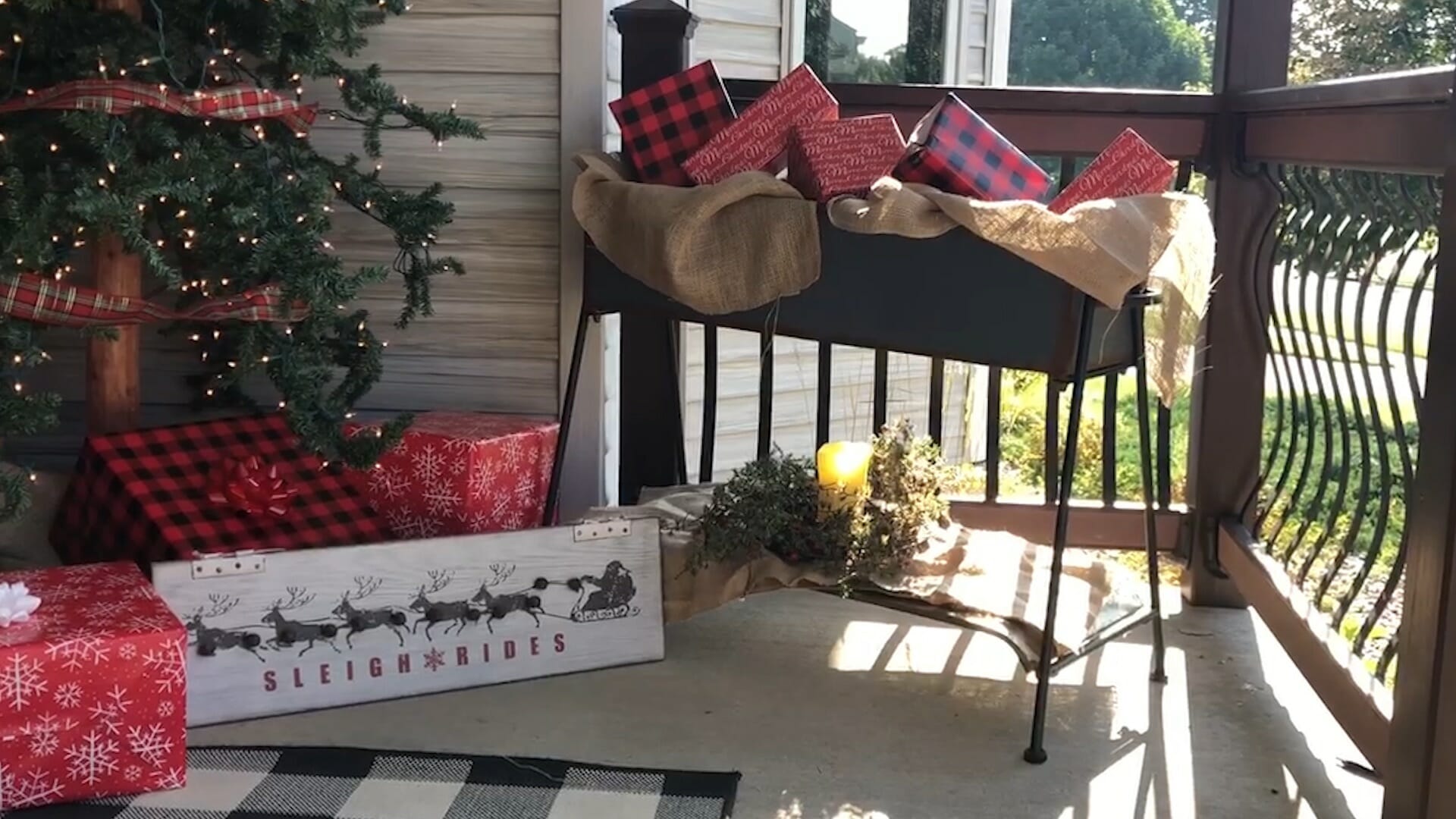 metal flower box filled with wrapped packages and burlap, wrapped gifts under a lit tree on front porch
