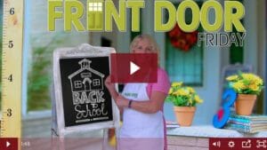 woman standing on front porch with back to school sign