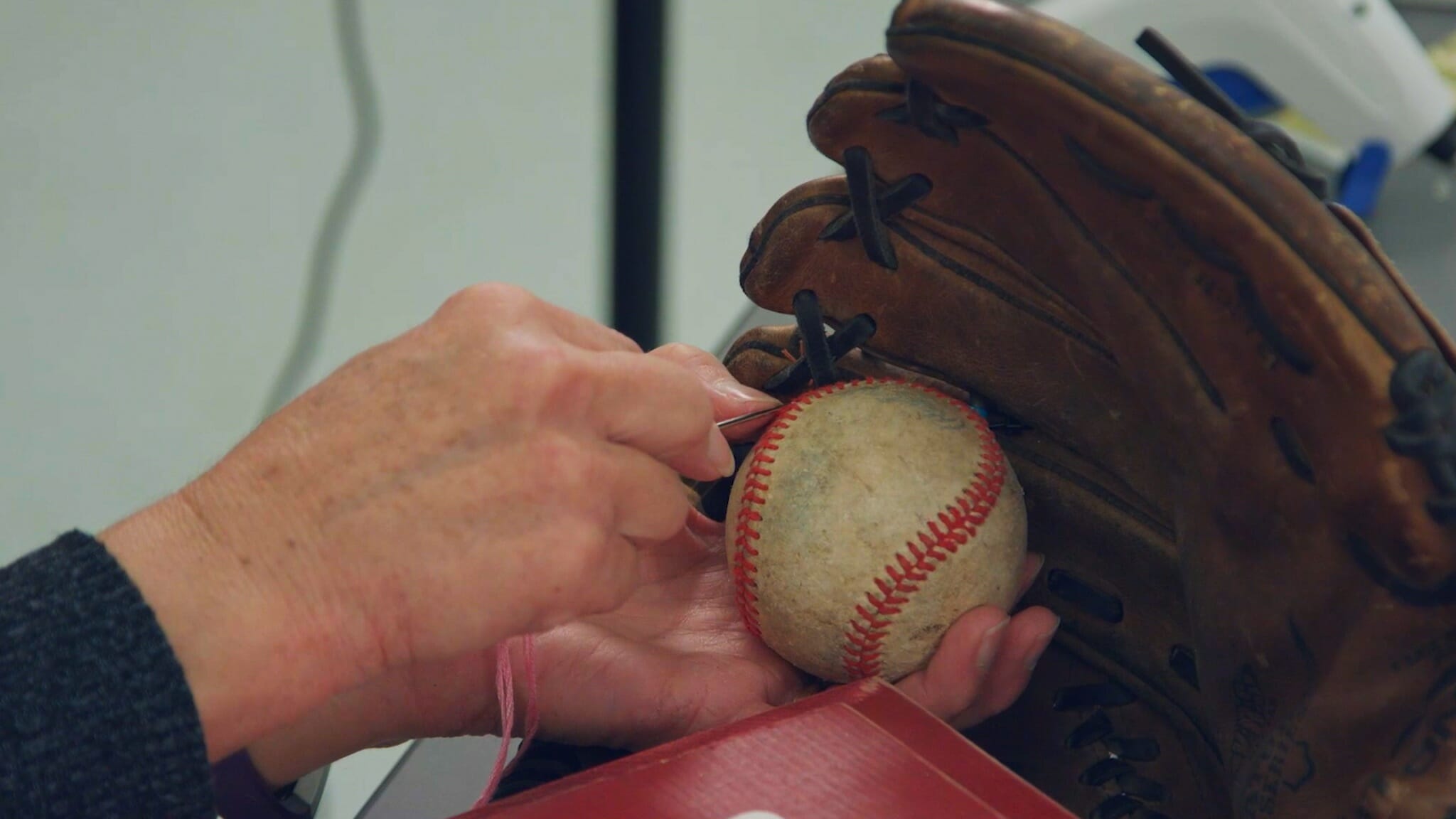 woman stitching baseball into catchers mitt for baseball themed wreath