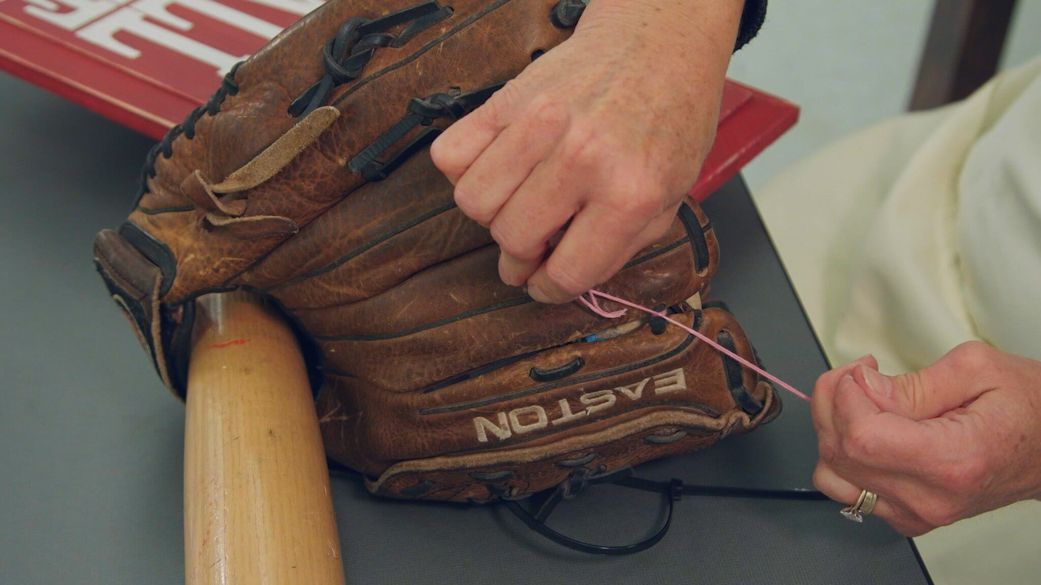 woman tying stitching off in back of catcher's mitt for baseball themed wreath