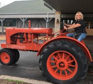 woman on an orange antique tractor