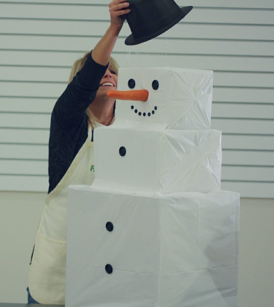 woman putting black top hat on Snowman