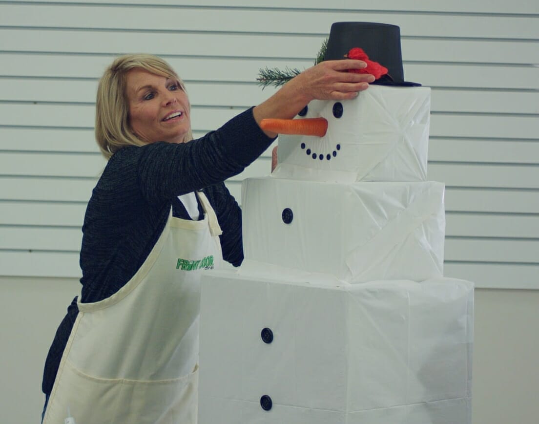 woman putting a hat on a snowman