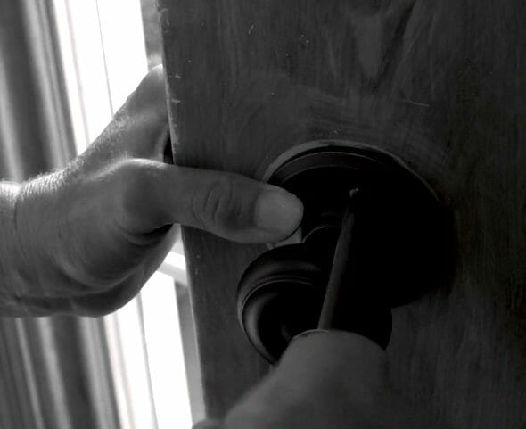 woman tightening new door knob on door