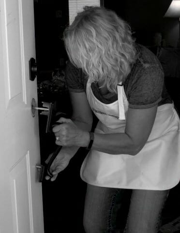 woman installing new door handle on door